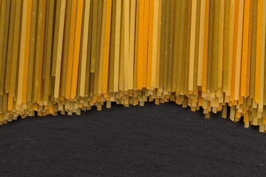 Bunch of raw italian pasta with vegetable dye of spinach, paprika and carrot