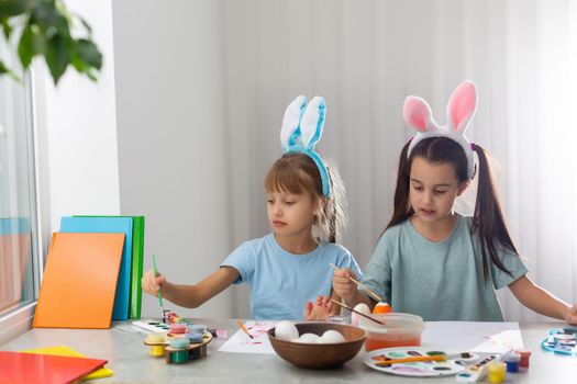 Happy easter. Two sisters painting Easter eggs. Happy family children preparing for Easter. Cute little child girl wearing bunny ears on Easter day.