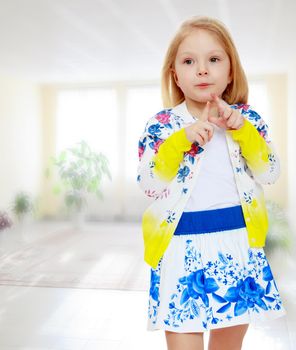 Pretty little blonde girl in a short summer skirt with Russian national ornament.