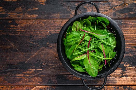 Fresh raw mixed greens, spinach, swiss chard and arugula. Dark wooden background. Top view. Copy space.