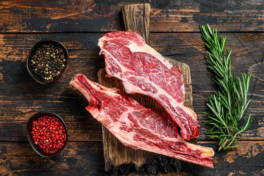 Fresh cuts of raw beef meat on a cutting board. Dark Wooden background. Top view.