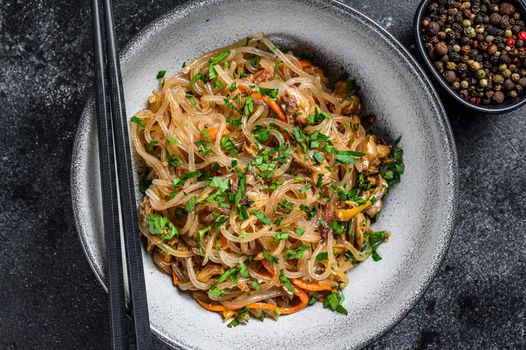 Wok Hot Asian cellophane noodles with chicken meat. Black background. Top view.