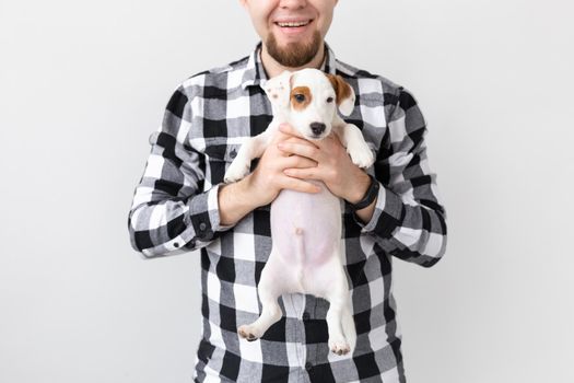 people, pets and dogs concept - young man hugging puppy on white background.