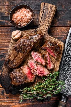 Grilled bbq skirt steaks slices on a wooden board. Dark wooden background. Top view.