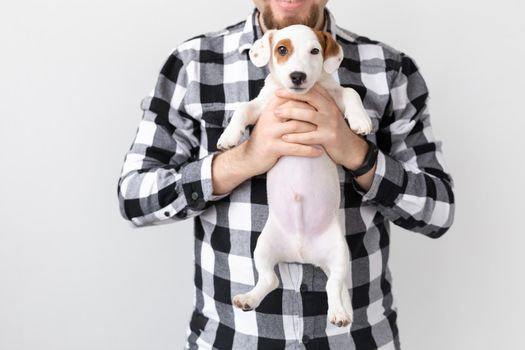 people, pets and animals concept - young man hugging puppy on white background.