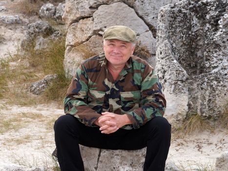 smiling middle aged man sitting on a stone, portrait