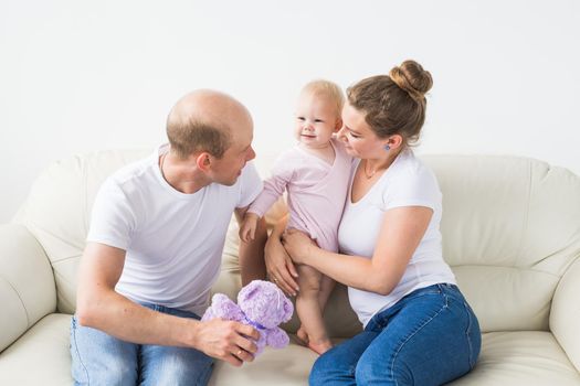 Smiling mother and father holding their newborn baby daughter at home