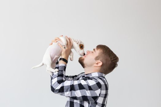 people, pets and animals concept - close up of young man holding jack russell terrier puppy on white background.