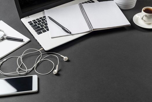Still life of office workplace with laptop and cup of coffee. Flat lay black surface with computer and open blank notebook. Paperwork, audit and accounting. Top view modern workspace with gadgets