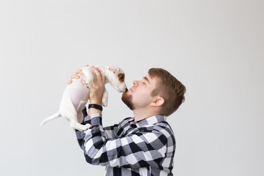 people, pets and animals concept - close up of young man holding jack russell terrier puppy on white background.