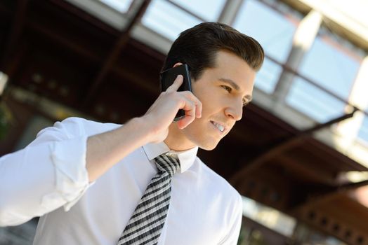Portrait of an attractive businessman making a call using a smart phone in an office building