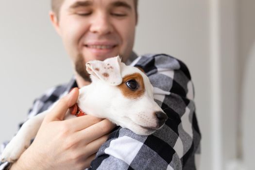 people, pets and animals concept - close up of young man holding jack russell terrier puppy.