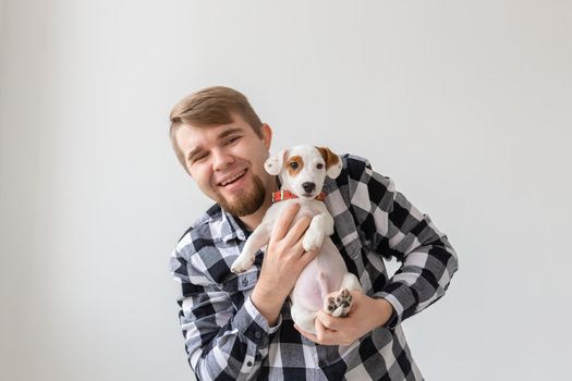 people, pets and animals concept - close up of young man holding jack russell terrier puppy on white background.
