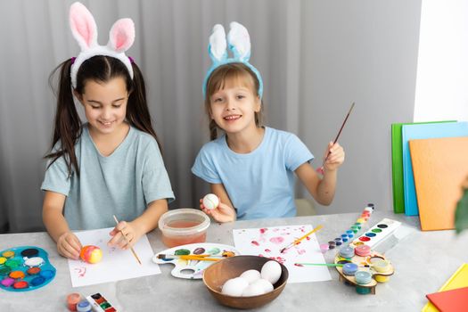 Happy easter. Two sisters painting Easter eggs. Happy family children preparing for Easter. Cute little child girl wearing bunny ears on Easter day.