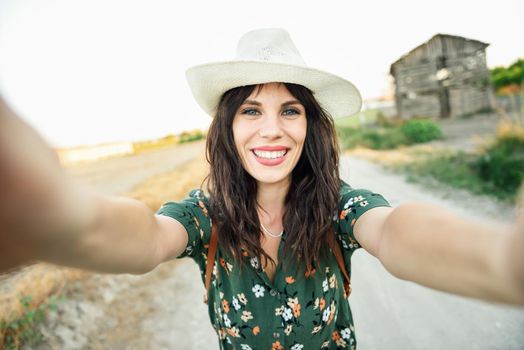 Beautiful hiker young woman, wearing flowered shirt, taking a selfie photograph outdoors