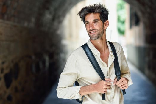 Young man sightseeing enjoying the streets of Granada, Spain. Male traveler carrying backpack in urban background.