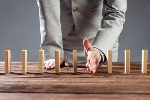 Business woman block domino effect. Business assistance, risk management and stabilisation situation. Intervention in process concept with wooden blocks on table. Protection from economic collapse.