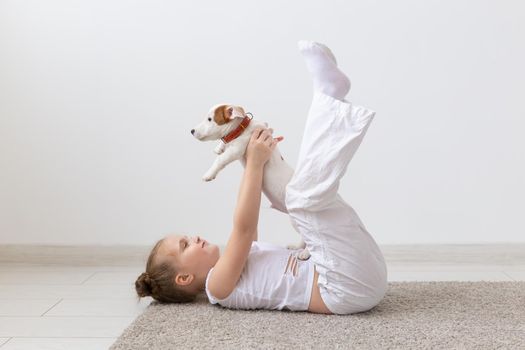 people, children and pets concept - little kid girl lying on the floor with cute puppy.