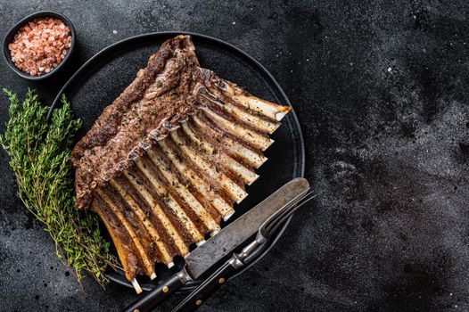 BBQ Grilled rack of Lamb mutton Ribs Chops on plate with thyme. Black background. Top view. Copy space.