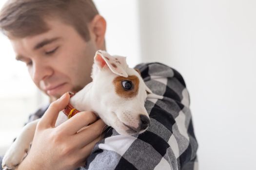 people, pets and animals concept - close up of young man holding jack russell terrier puppy.