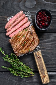 Sliced skirt beef meat steak on a cleaver. Black wooden background. Top view.