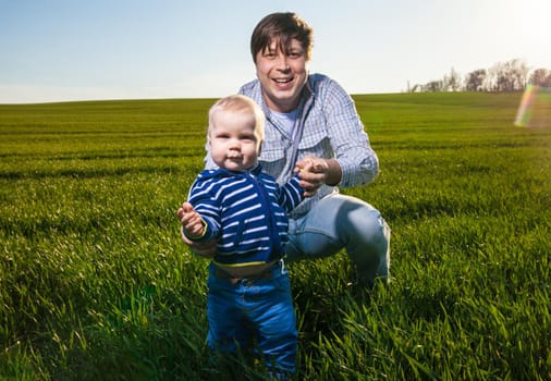 father and baby having fun, playing on green field