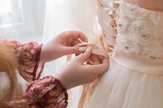 The girl's hands are tied behind the bride's wedding dress close-up.