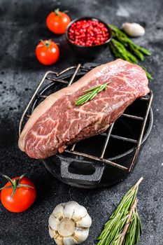 Raw rump cap steak on a grill. Black background. Top view.