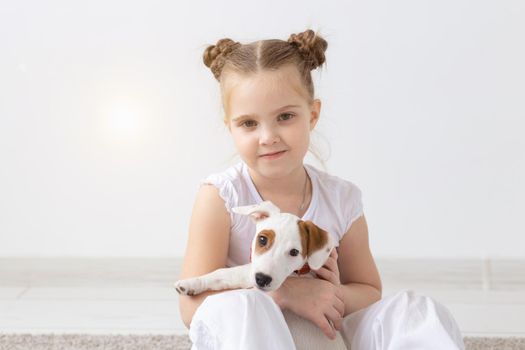 Dogs, pets and animal concept - Little child girl sitting with puppy Jack Russell Terrier.