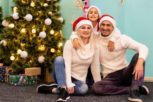 Merry Christmas and Happy Holidays. Cheerful mom and her cute daughter girl opening a Christmas present. Parent and little child having fun near Christmas tree indoors. View from inside of the box.