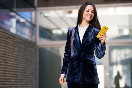 Business woman wearing blue suit using smartphone in an office building. Lifestyle concept.