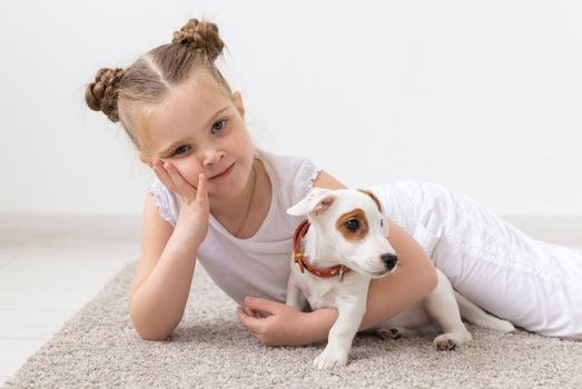 Childhood, pets and dogs concept - Little child girl posing on the floor with puppy.