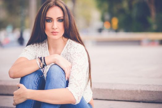 Portrait of a young woman, wearing casual clothes, with long hair in urban background