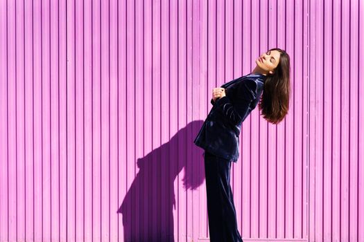Woman wearing blue suit posing near pink shutter. Lifestyle concept.