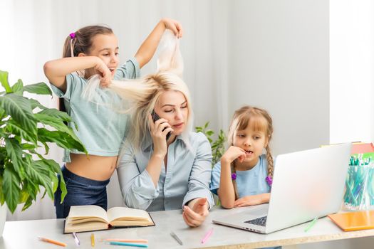 A young mother with two children works from home on a computer. Fatigue Lifestyle Housewife Freelance. tired mother and two little daughters