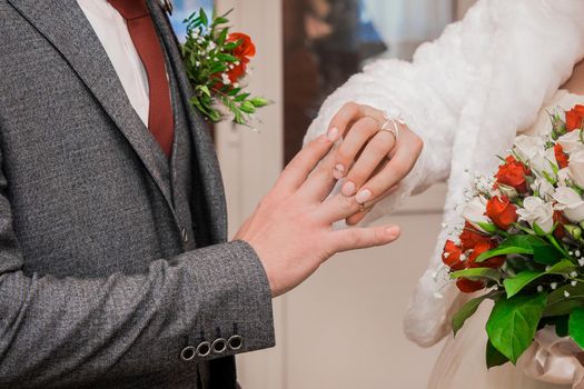 Bride's hand puts wedding ring on groom's thumbs up.