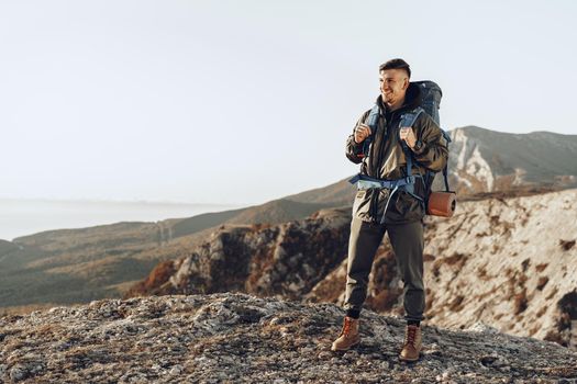 Young caucasian man traveler with big backpack hiking in the mountains alone