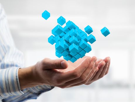 Close of businessman hand holding cube figure as symbol of innovation. 3D rendering