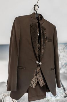 Luxury stylish brown men's suit with patterns and diamond clasp.