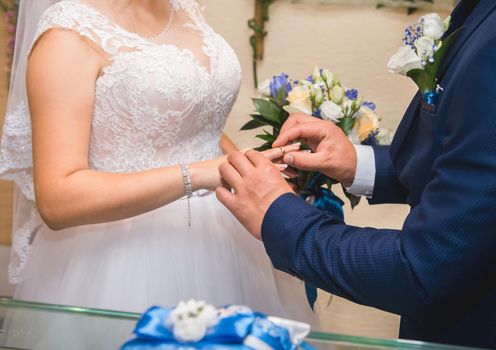 Sharing wedding rings. Groom puts ring on the bride's finger.