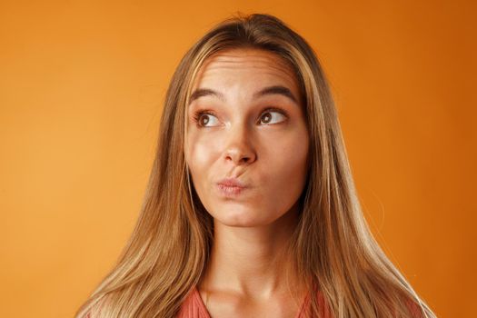 Studio portrait of beautiful young casual woman thinking close up