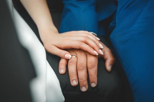 The hand of the young bride lies on the hand of the groom at the wedding, close-up.