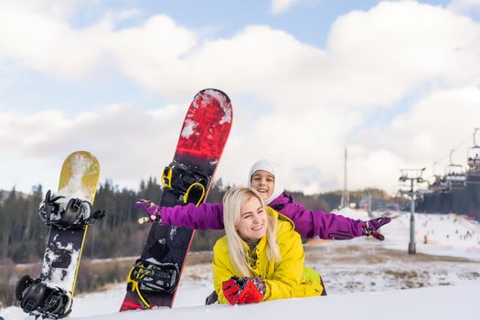 Mother and daughter with snowboards are playing in the snow