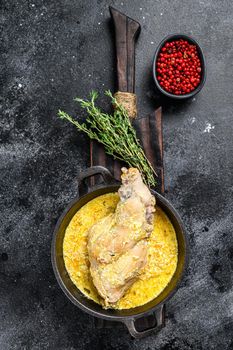 Roasted Rabbit Haunches in Pan with Stewed Vegetables. Black background. Top view.