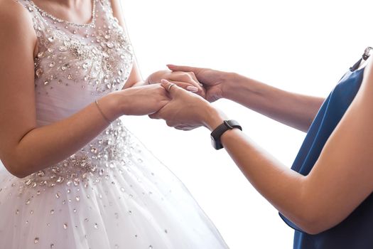 Mom and bride in white dress hold hands, close-up.
