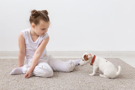 Children, pets and animal concept - Child girl play with her puppy indoors.