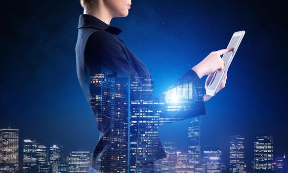 Businesswoman using tablet computer. Double exposure concept with night city and woman in business suit. Real estate investment and development. Digital technology in strategy planning and management.