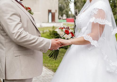 The bride and groom hold hands on a close-up wedding walk.