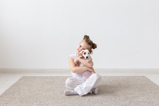 people, children and pets concept - little child girl sitting on the floor with cute puppy.