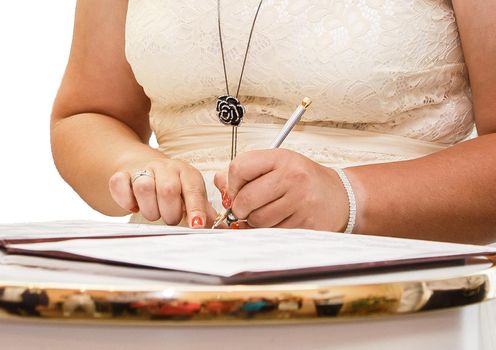 The girl's hands at the wedding put their signature pen in the magazine about marriage registration.
